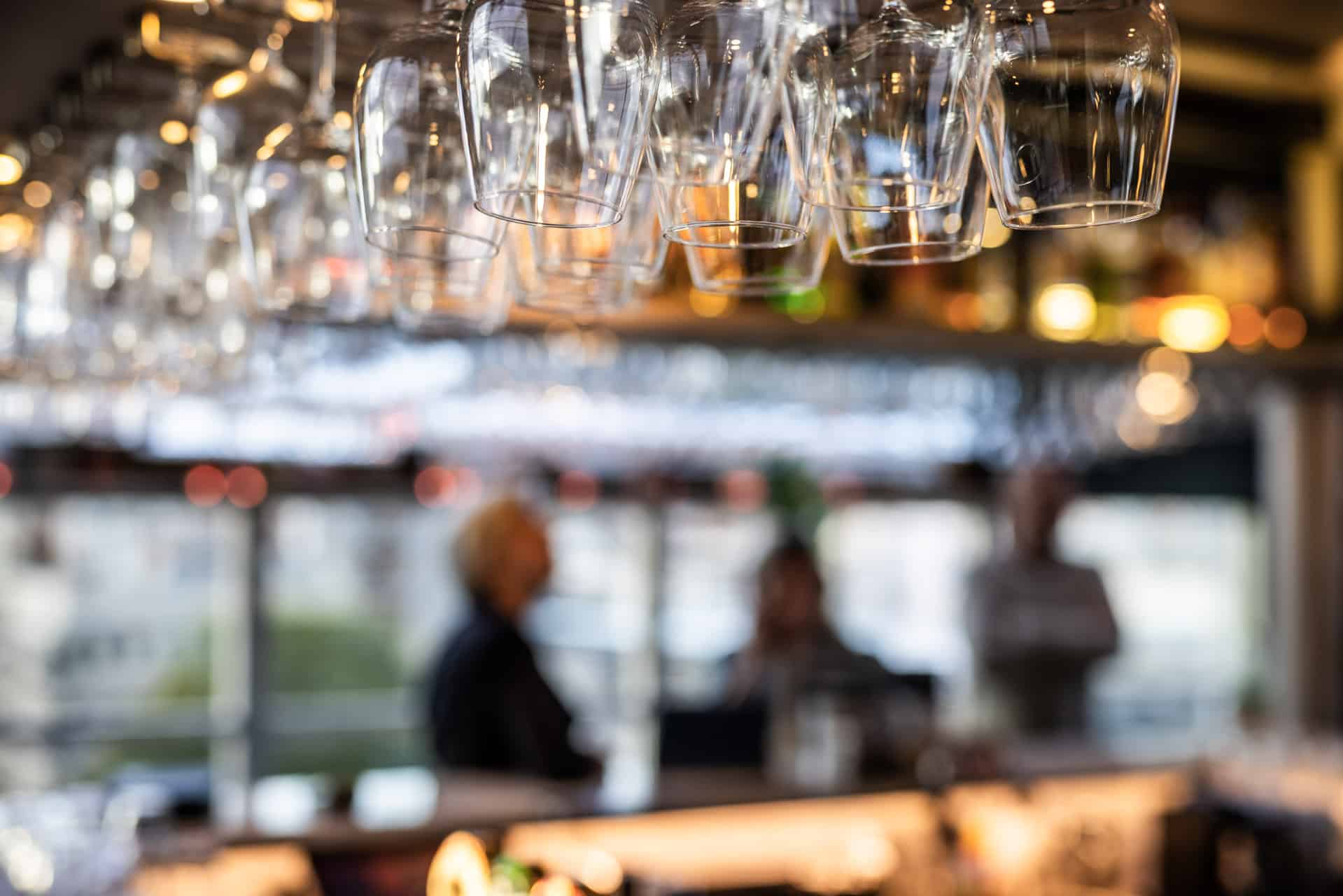 legant bardisk med hengende glass og varm belysning i Toppen Skybar.