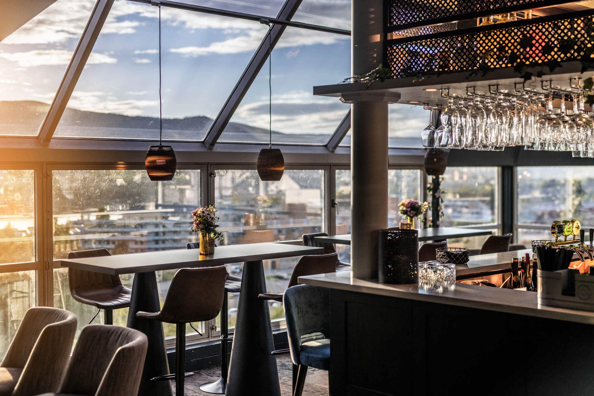 Toppen Skybar med store vinduer, sittegrupper og utsikt over Lillehammer.