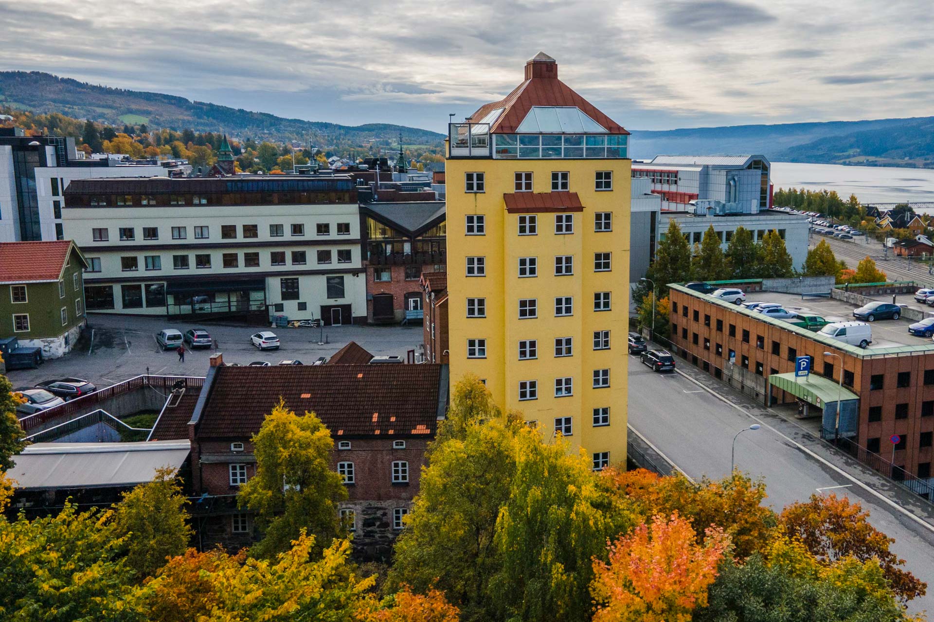 Aksjemøllen Boutiquehotell i Lillehammer med gult tårn og høstfargede trær.